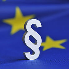 Paragrafenzeichen vor EU-Fahne | Bildquelle Fotolia Paragrafenzeichen vor europäischer Fahne
